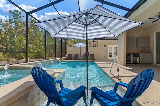 pool with french doors, an outdoor kitchen, glass enclosure, a patio area, and ceiling fan