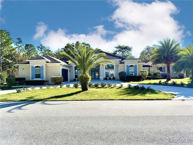 mediterranean / spanish home featuring a garage, concrete driveway, a front yard, and stucco siding