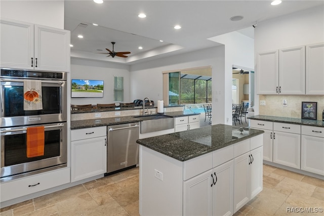 kitchen featuring appliances with stainless steel finishes, dark stone counters, and white cabinetry