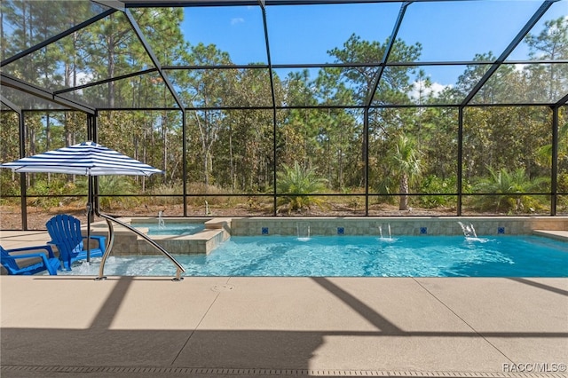 view of swimming pool featuring a pool with connected hot tub, glass enclosure, and a patio