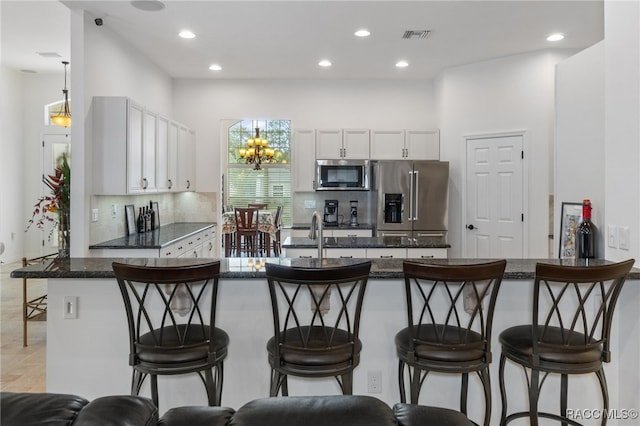 kitchen with stainless steel appliances, backsplash, a kitchen bar, and white cabinetry