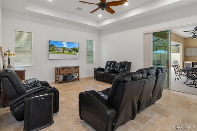 living room with ceiling fan, stone finish floor, a raised ceiling, and recessed lighting