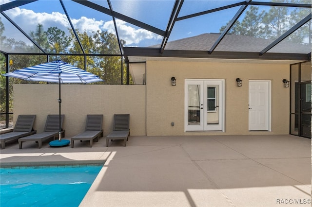 exterior space with an outdoor pool, glass enclosure, french doors, a patio area, and stucco siding