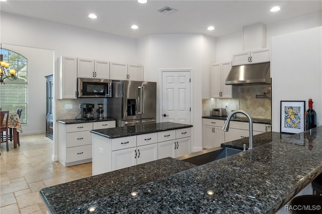 kitchen featuring a kitchen island with sink, under cabinet range hood, a sink, white cabinets, and appliances with stainless steel finishes