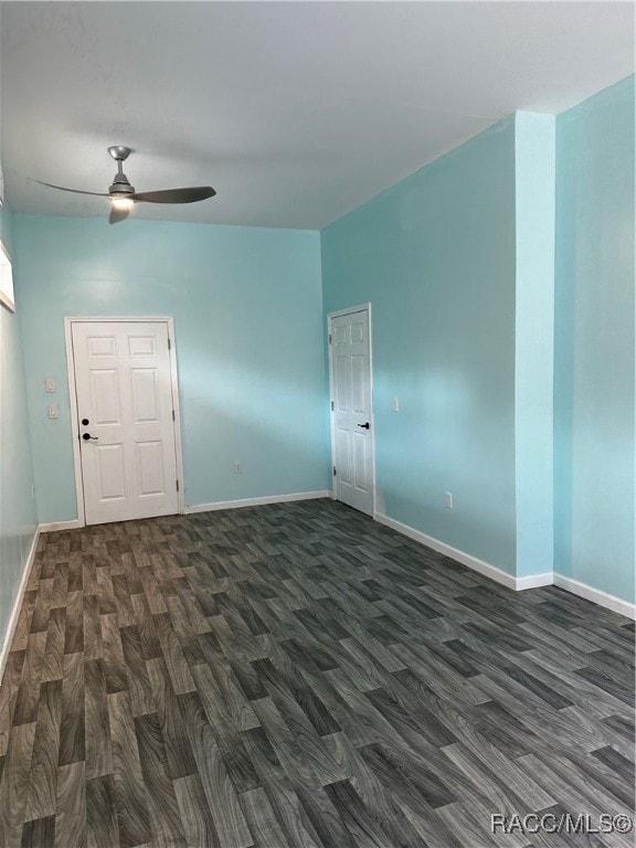 spare room with ceiling fan, dark wood-style flooring, and baseboards