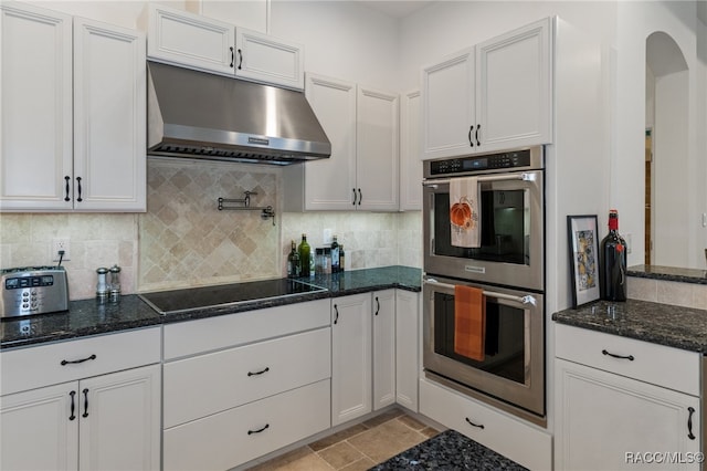 kitchen featuring under cabinet range hood, white cabinetry, black electric cooktop, and stainless steel double oven