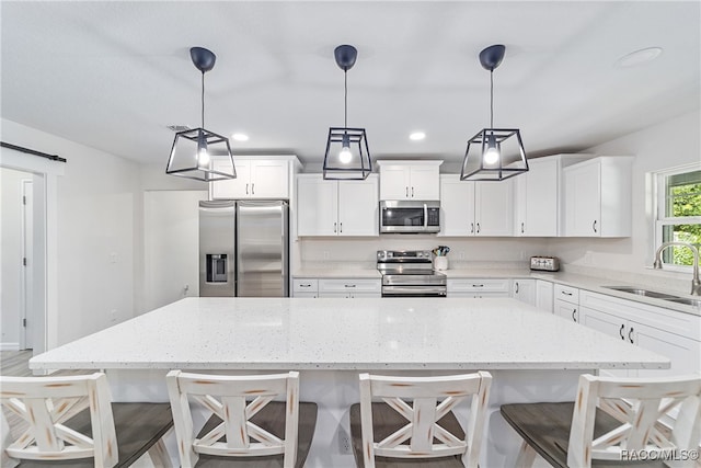 kitchen with sink, stainless steel appliances, decorative light fixtures, a breakfast bar area, and a kitchen island