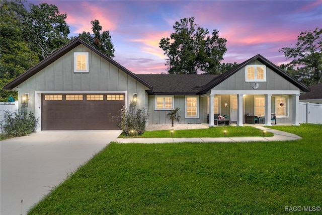 modern farmhouse featuring a lawn, a garage, and covered porch