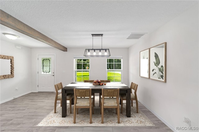 dining space featuring beamed ceiling, a textured ceiling, and light hardwood / wood-style flooring