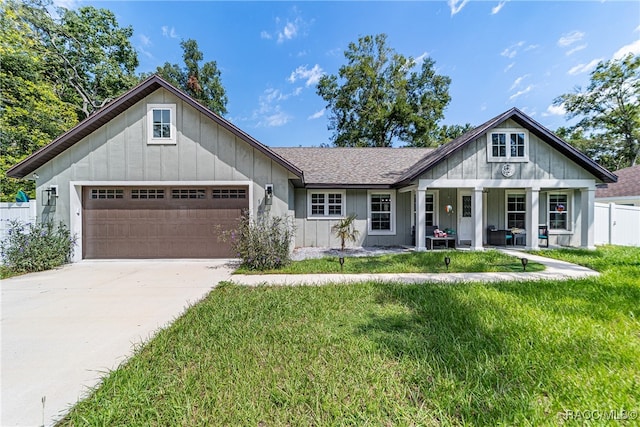 view of front of house with covered porch, a garage, and a front lawn