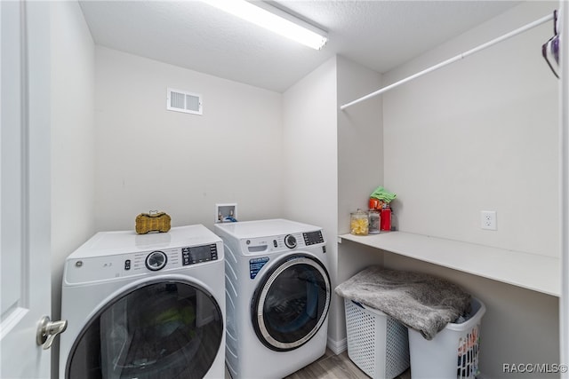 washroom with washer and dryer, hardwood / wood-style floors, and a textured ceiling