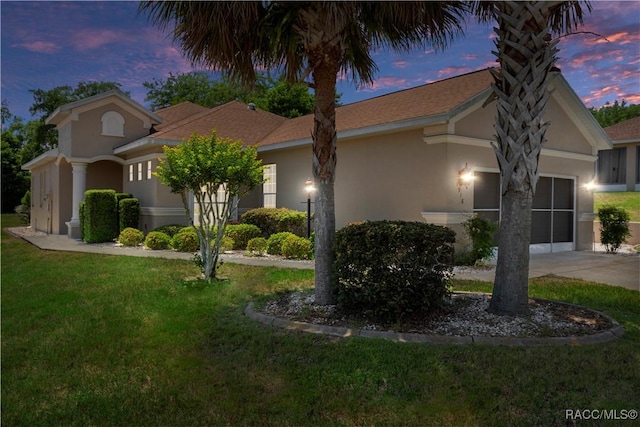 1918 W Crystal Mae Path, Lecanto, FL 34461 - property exterior at dusk with an attached garage, stucco siding, and a yard