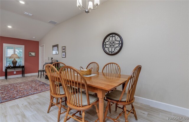 dining space featuring a notable chandelier, light hardwood / wood-style floors, and vaulted ceiling