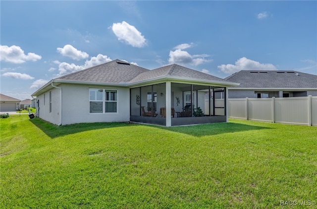 rear view of house featuring a sunroom and a lawn