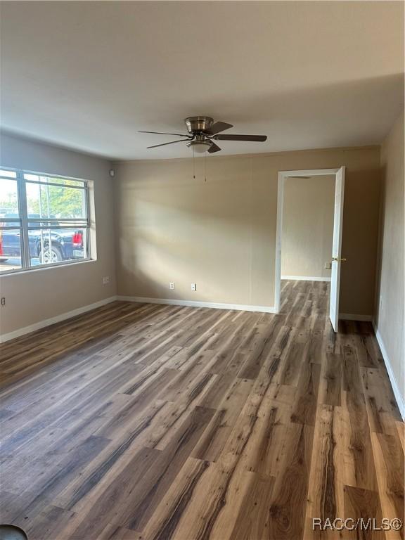 unfurnished room with ceiling fan and dark wood-type flooring