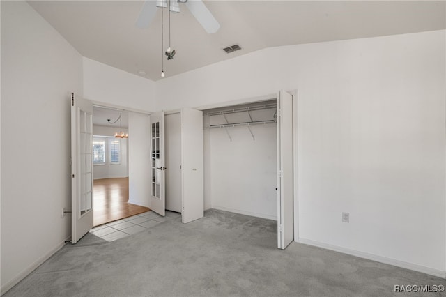 unfurnished bedroom featuring french doors, light colored carpet, lofted ceiling, a closet, and ceiling fan with notable chandelier