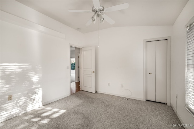 unfurnished bedroom with ceiling fan, a closet, light colored carpet, and lofted ceiling