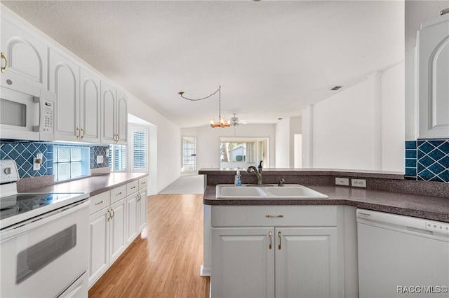 kitchen with white cabinetry, sink, white appliances, and an inviting chandelier