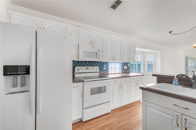 1868 W Shanelle Path, Lecanto, FL 34461 - kitchen with white appliances, white cabinetry, light wood finished floors, backsplash, and dark countertops