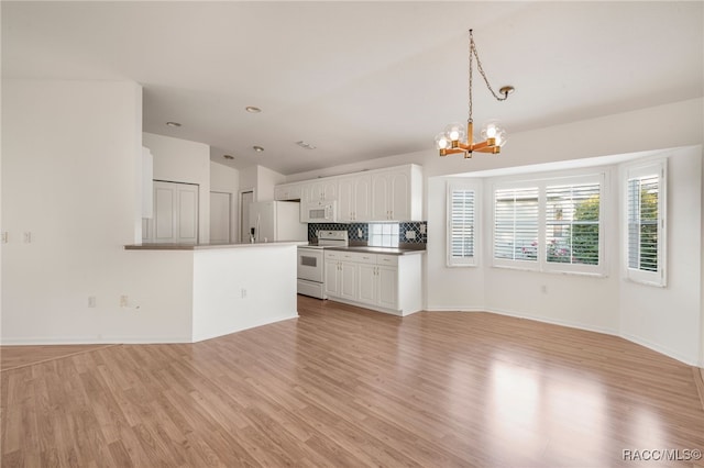 unfurnished living room featuring light hardwood / wood-style flooring, a chandelier, and lofted ceiling