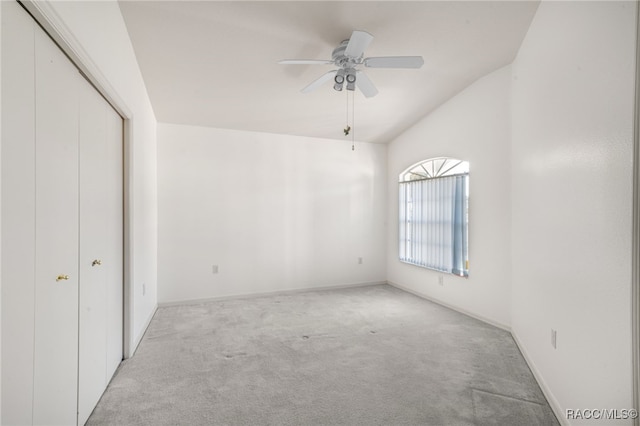 unfurnished bedroom featuring ceiling fan, light colored carpet, lofted ceiling, and a closet