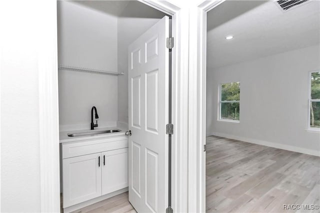 bar featuring sink, a wealth of natural light, white cabinets, and light wood-type flooring