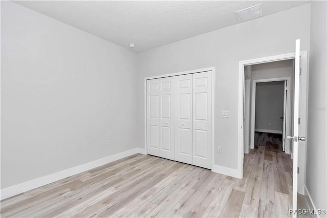 unfurnished bedroom featuring a closet, a textured ceiling, and light wood-type flooring