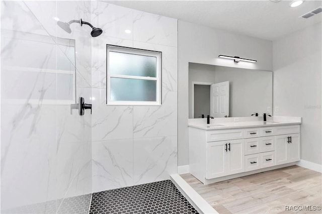 bathroom with vanity, hardwood / wood-style floors, and tiled shower