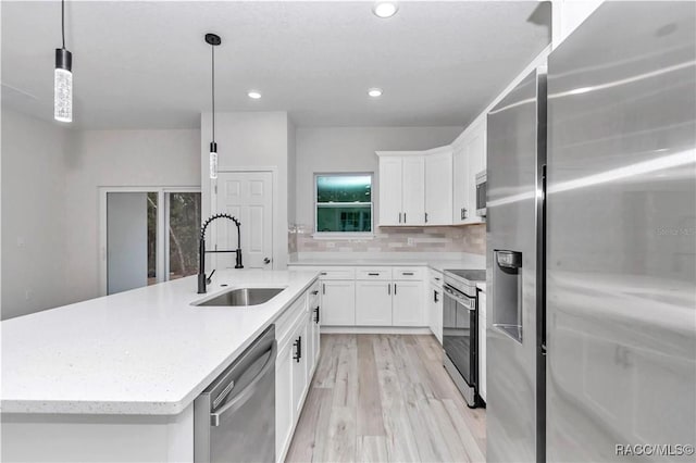 kitchen with pendant lighting, stainless steel appliances, sink, and white cabinets