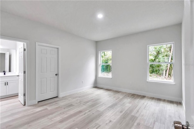 unfurnished bedroom with sink, light hardwood / wood-style floors, and ensuite bathroom