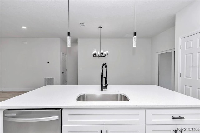 kitchen with sink, dishwasher, an island with sink, pendant lighting, and white cabinets