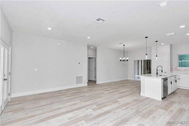 kitchen featuring pendant lighting, sink, dishwasher, a kitchen island with sink, and white cabinets