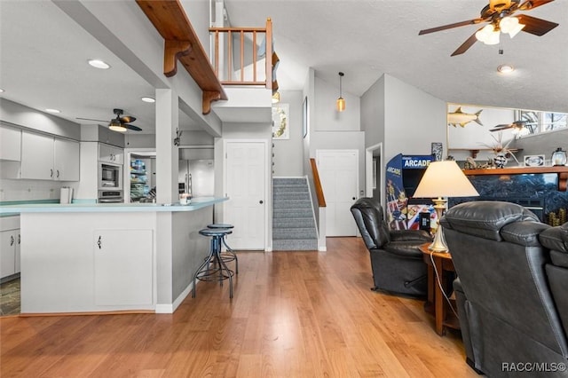 kitchen featuring light hardwood / wood-style flooring, ceiling fan, appliances with stainless steel finishes, hanging light fixtures, and white cabinets