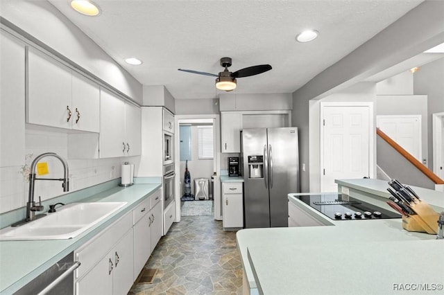 kitchen featuring stainless steel appliances, sink, white cabinets, and backsplash