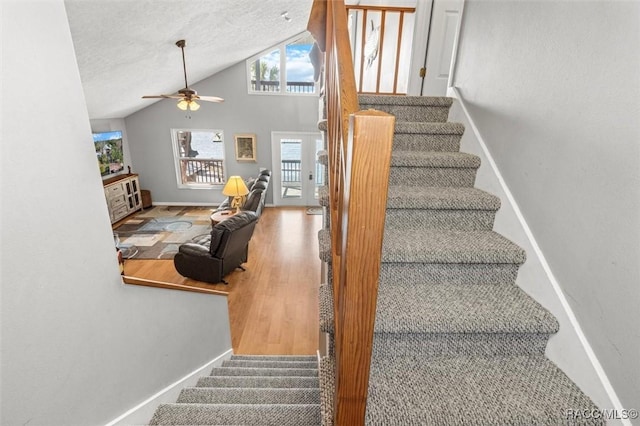 stairway featuring ceiling fan, high vaulted ceiling, hardwood / wood-style floors, and a textured ceiling