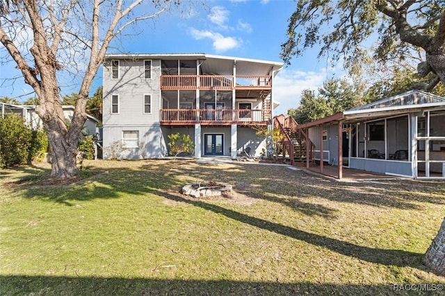 back of property featuring a fire pit, a sunroom, and a lawn