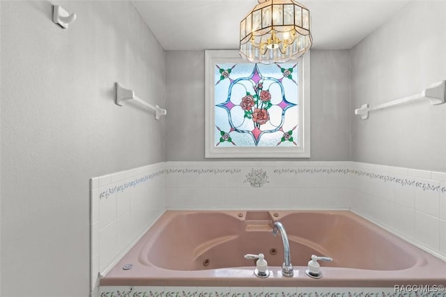 bathroom featuring tiled bath and an inviting chandelier