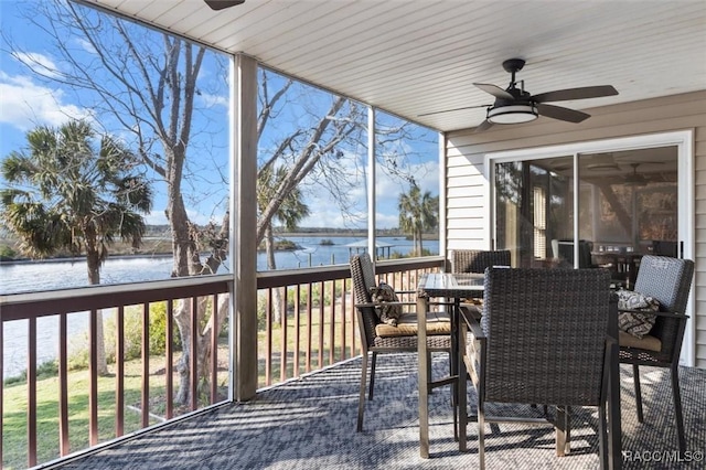 sunroom with a healthy amount of sunlight, ceiling fan, and a water view