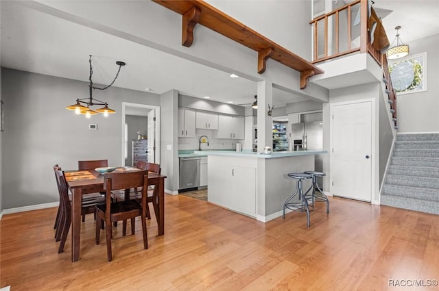 kitchen with pendant lighting, sink, light hardwood / wood-style floors, and appliances with stainless steel finishes