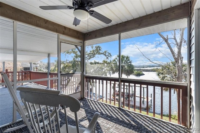 sunroom / solarium featuring a wealth of natural light, ceiling fan, and a water view