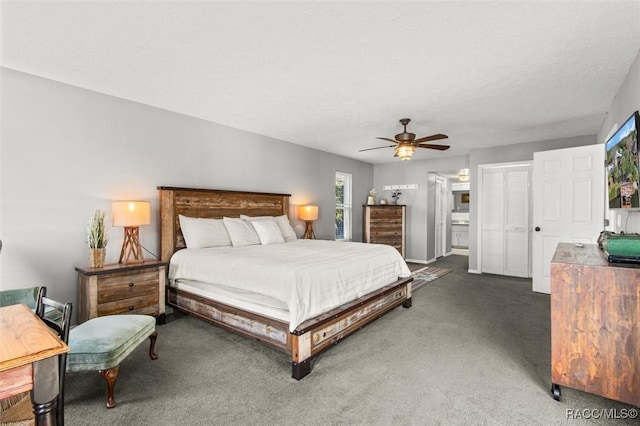 bedroom with ceiling fan, connected bathroom, a textured ceiling, and dark carpet