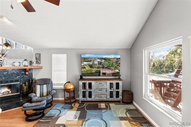 living room featuring ceiling fan, a fireplace, vaulted ceiling, and hardwood / wood-style floors