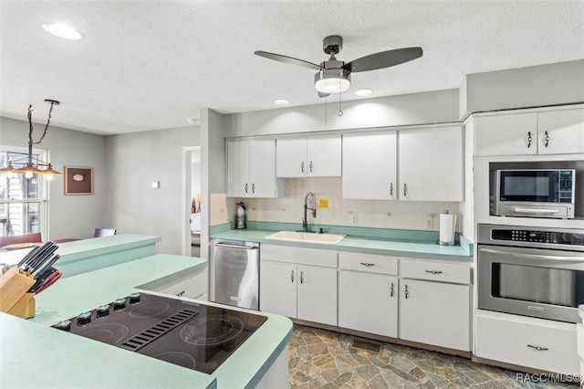 kitchen with appliances with stainless steel finishes, pendant lighting, sink, white cabinets, and backsplash