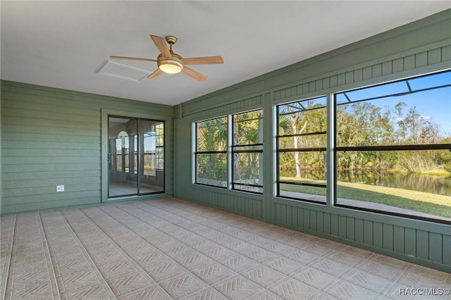 unfurnished sunroom with a wealth of natural light, a water view, and ceiling fan