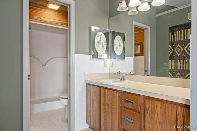 bathroom featuring tile patterned flooring, toilet, vanity, tile walls, and ornamental molding