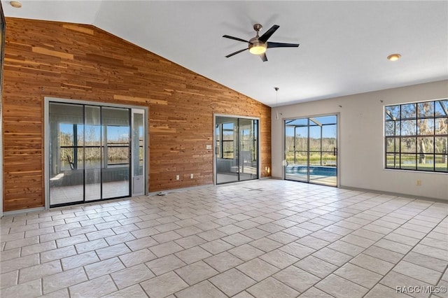 spare room with light tile patterned floors, ceiling fan, lofted ceiling, and wood walls