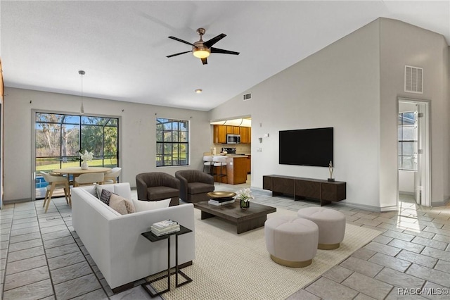 tiled living room featuring ceiling fan and high vaulted ceiling