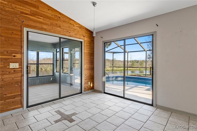 entryway with wooden walls, light tile patterned floors, a water view, and vaulted ceiling