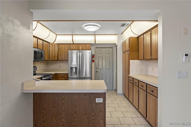 kitchen featuring decorative backsplash, light tile patterned floors, kitchen peninsula, and appliances with stainless steel finishes