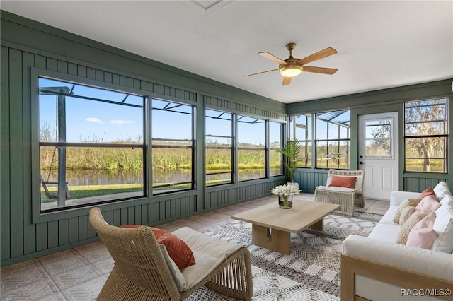 sunroom / solarium featuring a wealth of natural light, ceiling fan, and a water view